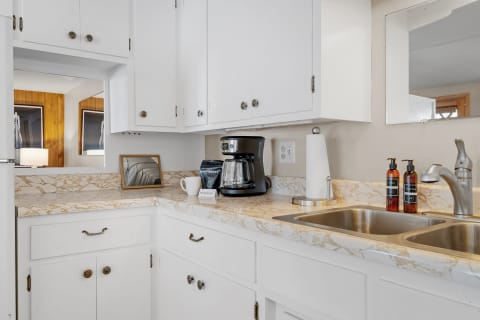 A well-organized kitchen featuring a coffee maker, mug, and marble countertop with white cabinets.