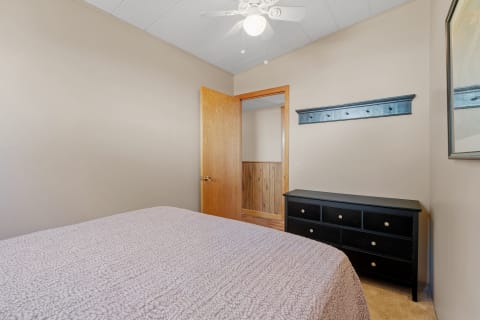 A simple bedroom with a bed, wooden dresser, and a shelf with hooks.
