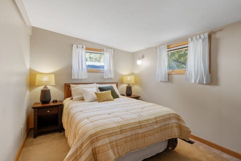 A cozy bedroom featuring a striped comforter and warm lighting.