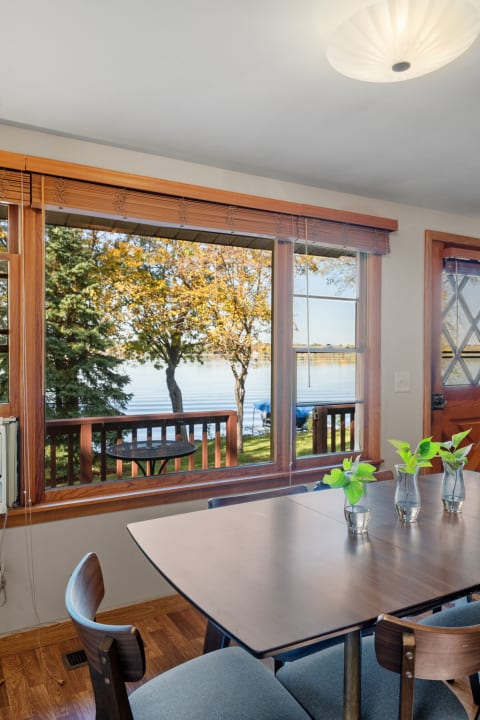 Cozy dining space with a view of the lake and autumn trees outside.