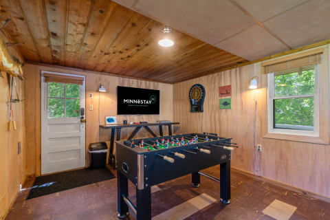 An indoor game room with a foosball table and dartboard in a cozy cabin setting.