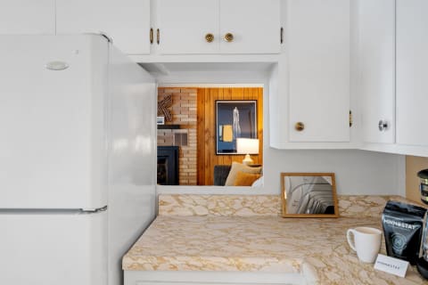 A kitchen with white cabinetry and a view into a warmly lit living room.