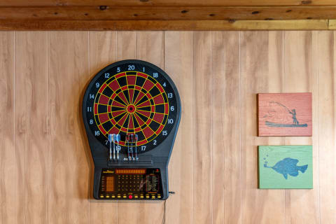 Dartboard with digital scoring system and fishing-themed wooden wall plaques.