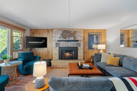 Living room with a sectional sofa, fireplace, and large windows, showcasing warmth and comfort.