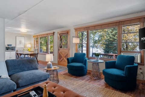 Living room featuring teal chairs, a comfortable sofa, and large windows with a view of nature.