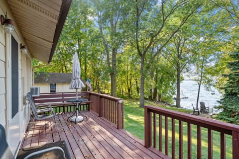 Lakeside deck with chairs and round table overlooking the water.