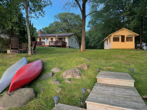 Lakeside house with a guest cabin and kayaks on the shore.