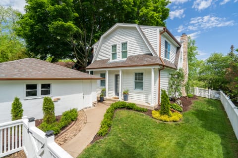 Two-story house with gray siding, a brown shingle roof, and a front garden.