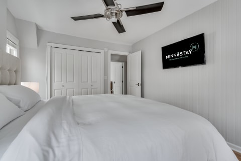 Cozy bedroom with a king-size bed, bedside lamp, and mounted TV.