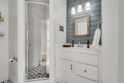 Stylish bathroom with glass shower, white vanity, and blue shiplap wall.