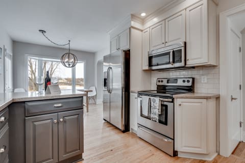 A contemporary kitchen featuring a central island, stainless steel appliances, and a large window.