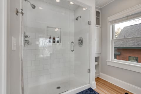 Spacious modern shower with glass door and white subway tile walls.
