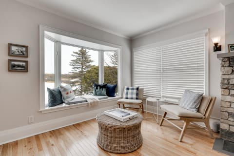 Cozy living room with bay window, wooden floor, and decorative pillows.