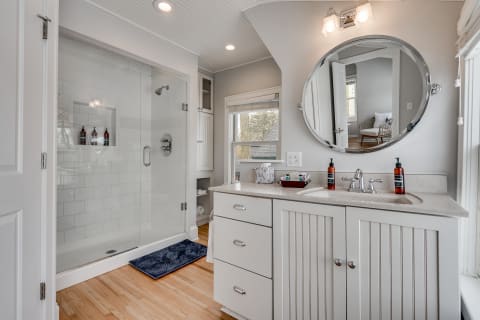 A modern bathroom with a glass shower, double sink vanity, and natural lighting.