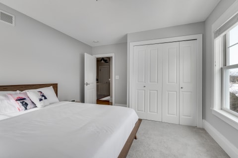 A modern bedroom featuring a wooden bed and grey walls.