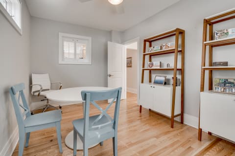 A modern home office with a round table, blue chairs, and a contemporary bookshelf.