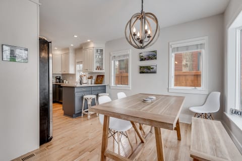 Contemporary kitchen dining area with wooden flooring, a rustic table, and stylish chandelier.