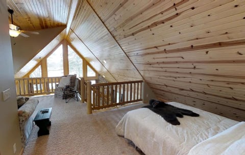 Attic bedroom with wooden ceiling, sofa, and double bed.