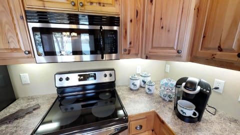 Interior view of a rustic kitchen with wooden cabinets, stainless steel appliances, and moose-themed decor.