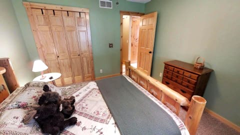 A rustic bedroom with a wooden bed, plush toys, and green walls.