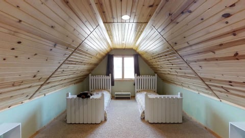 Attic bedroom with wooden ceiling and two twin beds.