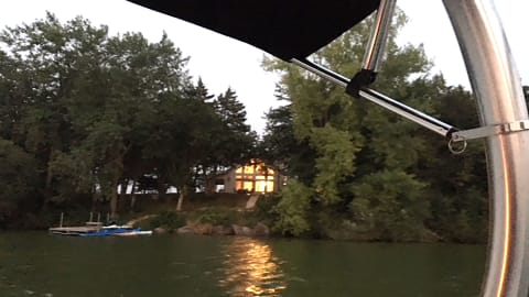 Lakeside scene with a glowing house and a dock at dusk.