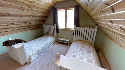 Cozy attic bedroom featuring two twin beds with white wooden headboards and floral bedding.