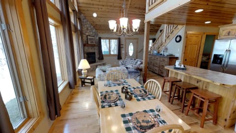 Interior of a rustic cabin featuring a dining table, living area, and wooden finishes.