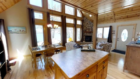 Interior of a cozy cabin showcasing a dining area, living space, and large windows with a lake view.