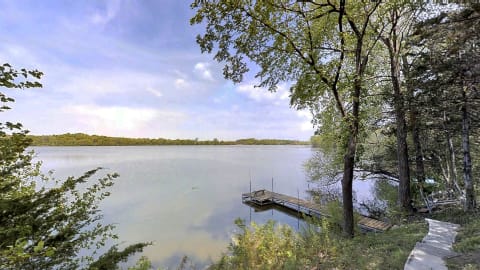 Lakeside scene with a wooden dock and trees surrounding calm waters.