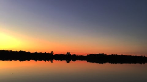 A sunset scene over a lake with reflections on the water.
