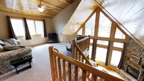 Spacious living room with wooden ceiling, large windows, and floral sofa.