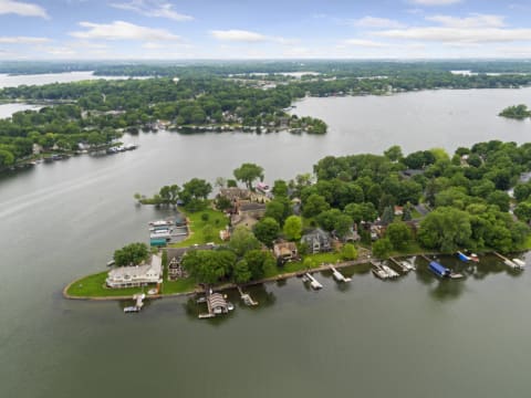 Aerial view capturing a serene lake dotted with houses and boats, bordered by greenery.
