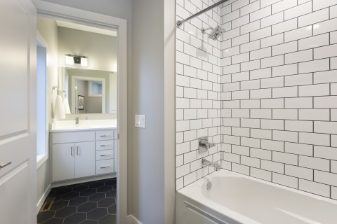 Contemporary bathroom with white subway tiles, black hexagon tiles, and a double sink vanity.