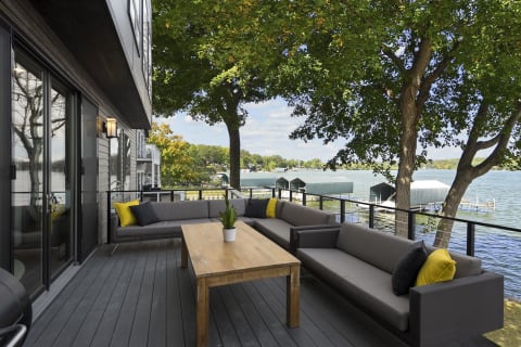 Modern outdoor lounge area with lake view and greenery.