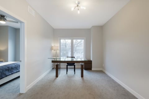 Modern home office with glass desk and window view.