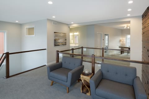 Modern interior loft with grey armchairs, a wooden accent table, and bright decor.