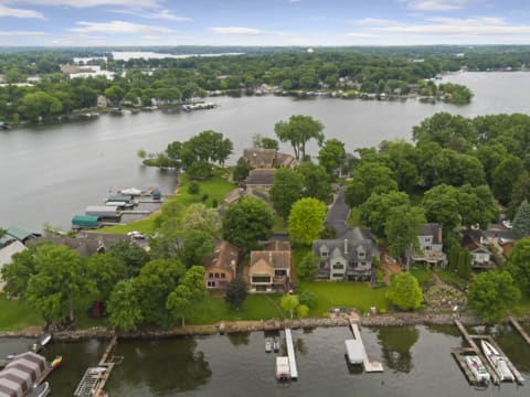 Aerial view of homes by a lake, surrounded by trees and boats.