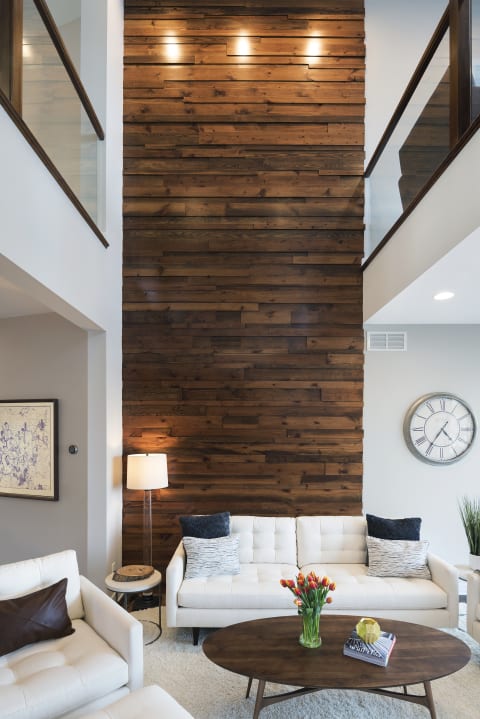 Modern living room with white sofas, wooden wall, and decorative accents.