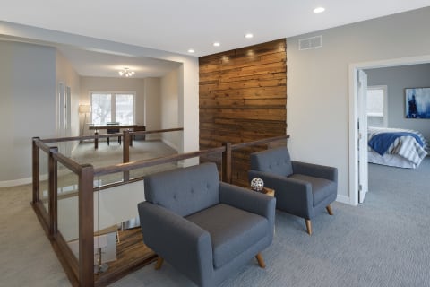Cozy modern interior with gray armchairs, wooden accents, and a workspace.