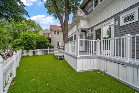 Outdoor view of a house with a green lawn and a white picket fence.
