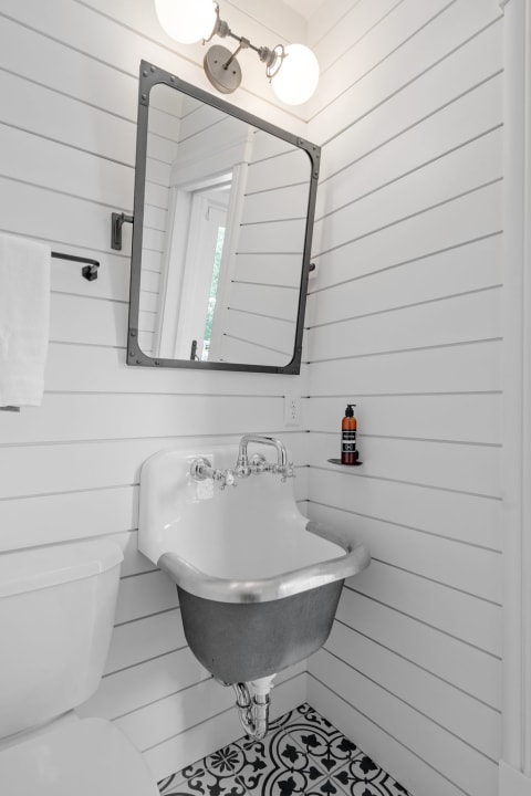Compact bathroom with shiplap walls, vintage sink, and patterned floor tiles.