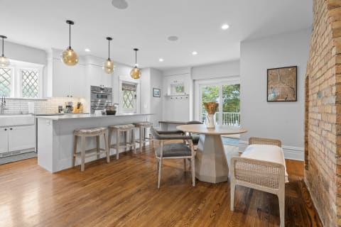 Modern kitchen with white cabinetry, dark wood flooring, and a dining area.
