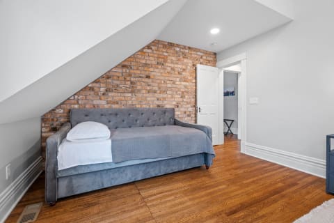 Cozy bedroom with daybed and exposed brick wall.