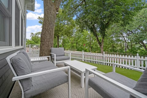 Outdoor patio with modern grey and white furniture amidst trees.