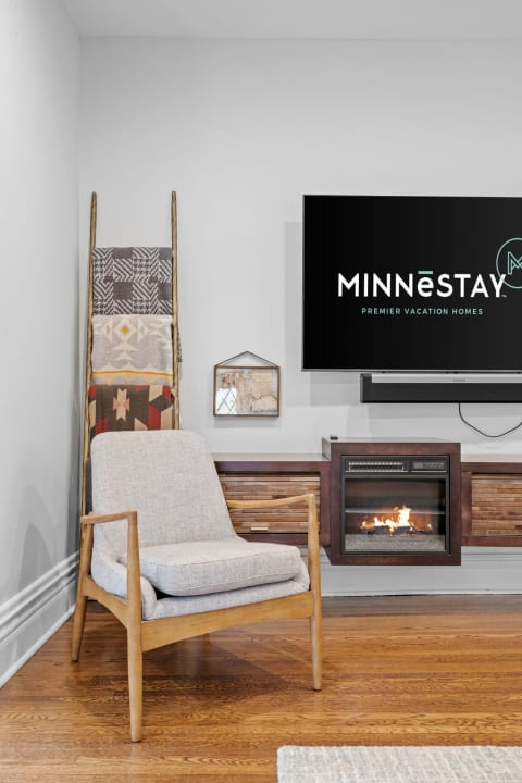 Cozy living room with an armchair, blankets, and a television displaying MINNESTAY logo.
