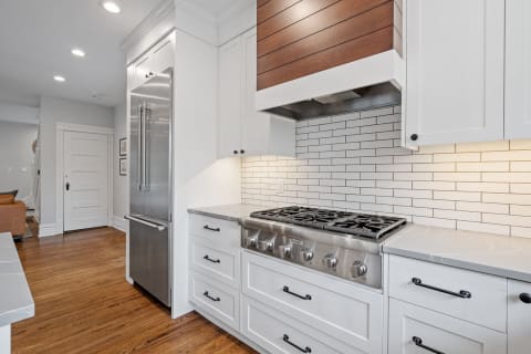 Interior view of a contemporary kitchen with a gas range and stainless steel fridge.