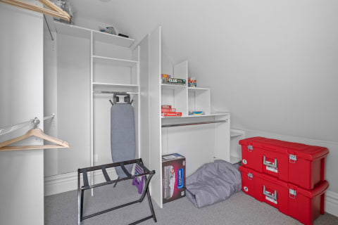 Tidy attic storage area featuring shelves, an ironing board, and red storage boxes.