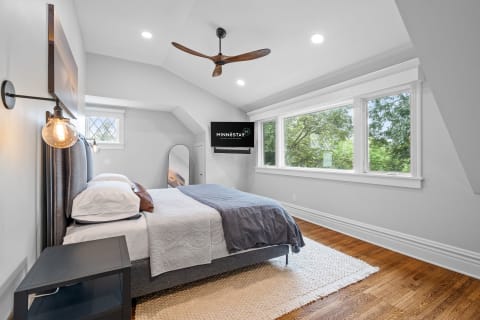 A modern bedroom featuring a bed, nightstands, and large windows with views of greenery.