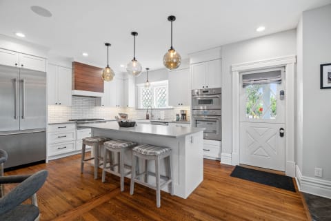 Modern kitchen featuring a central island with stools, stainless steel appliances, and stylish lighting.